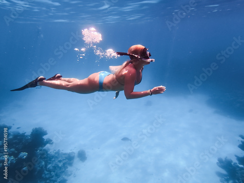 Fotografía Blonde woman snorkeling underwater in the clear blue Red Sea, Egypt, exploring a coral reef