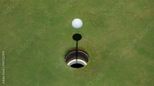 Golf ball on green grass near hole with flagstick