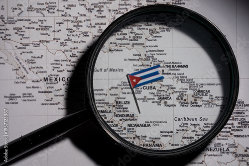 Magnifying glass focusing on a Cuba flag pin on a world map over the Caribbean, representing geopolitical research, regional analysis, and international diplomacy