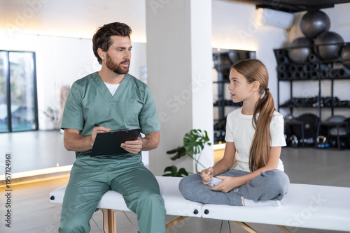 Male doctor talking to young girl during consultation