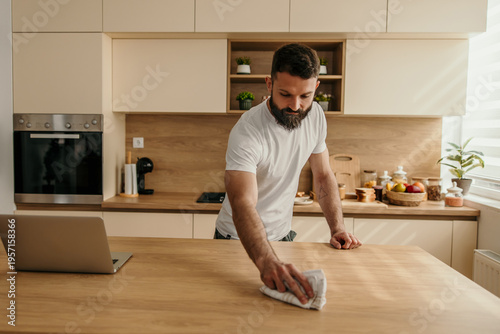 Photos Young male cleaning kitchen countertop