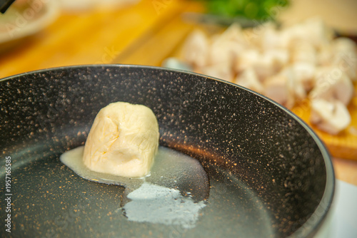 Canvas Print A piece of butter melts in a pan against the background of sliced mushrooms and vegetables
