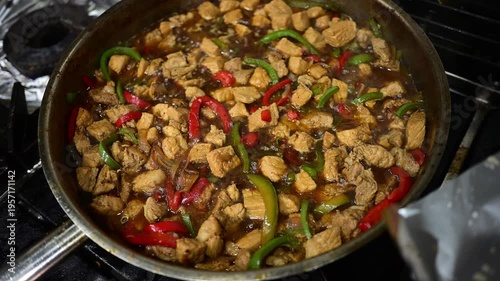 Pork stir-fry simmers in a pan on a stove