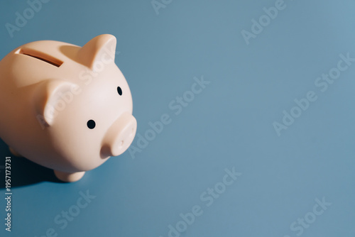 Piggy bank savings finance money investment blue background ceramic coin slot minimal isolated object banking economy cash budget wealth financial planning protection secure deposit thrift