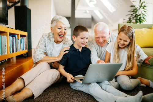 Grandparents and grandchildren using laptop in living room