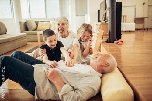 Grandparents tickling grandchildren on living room floor