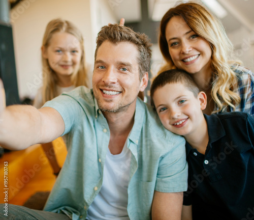 Smiling family of four taking selfie at home