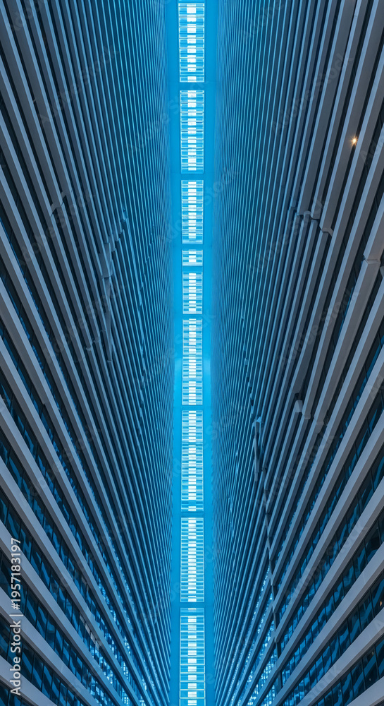 Fototapeta premium Low angle shot of building exterior with parallel stripes, illuminated by blue light, creating a modern, futuristic architectural aesthetic