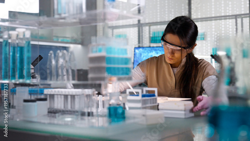 Female scientist in protective gear working in a laboratory to test human DNA samples. Preparing test samples for examination with a pipette. Selective focus