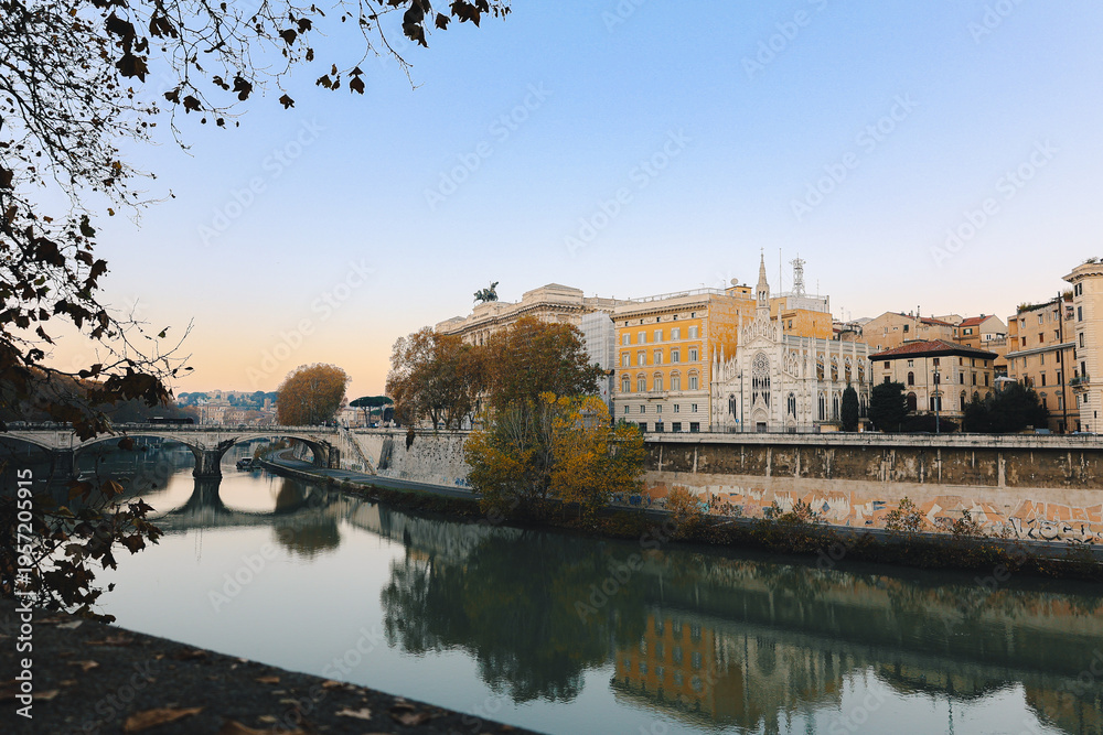 Fototapeta premium Classical architecture and arched bridge over river with soft evening tones and reflections creating timeless urban landscape in Italy.