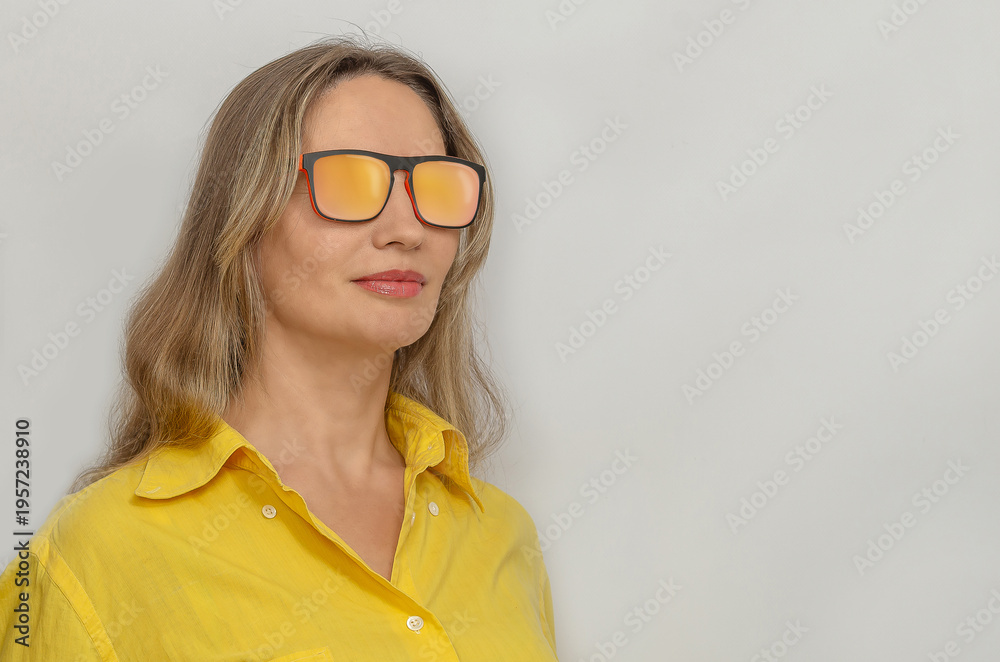 Fototapeta premium Confident woman in yellow shirt wearing stylish sunglasses isolated on light background. Copy space.