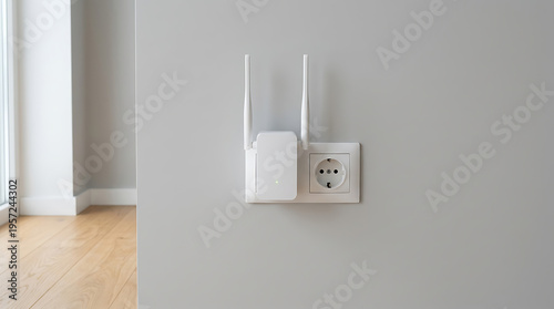 White wifi router plugged into electrical outlet on gray wall in modern room with wooden floor