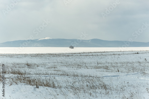 A snow-covered field and the Sayan Mountains in the background. Nature of Eastern Siberia, Russia, Sayan mountains