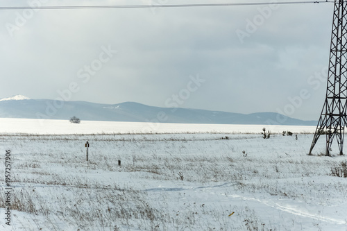 A snow-covered field and the Sayan Mountains in the background. Nature of Eastern Siberia, Russia, Sayan mountains