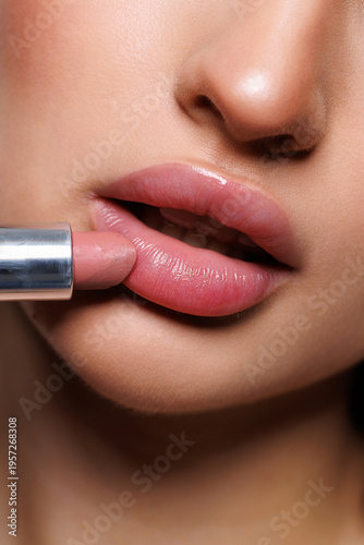 Smiling woman applying lip balm onto her lips, closeup