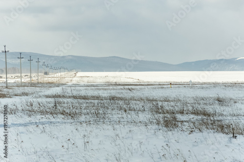 Winter landscape with snow-covered field and mountains in the background.