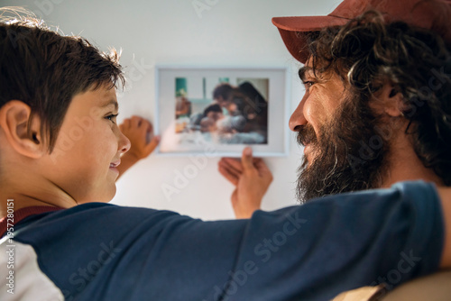 Father and son hanging framed family photo at home