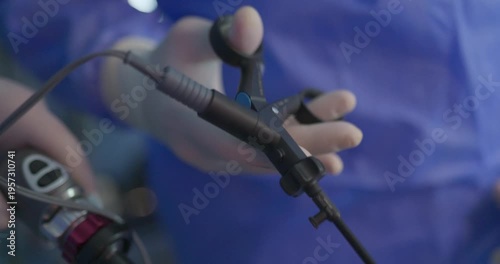 Close-up of a surgeon’s gloved hand holding a laparoscopic grasper instrument during a minimally invasive surgical procedure.