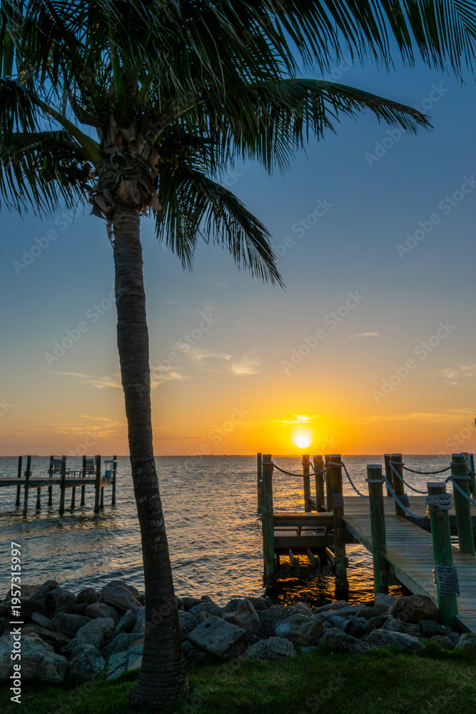 Fototapeta premium Boat pier and palm trees, sunset landscape on the Banana River in Cocoa Beach, Florida