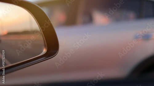 View in the rear view side mirror of a automobile, driving a red car along the road