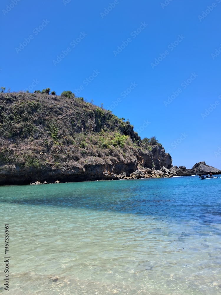 Naklejka premium clear turquoise water near a rocky cliff under a bright blue sky