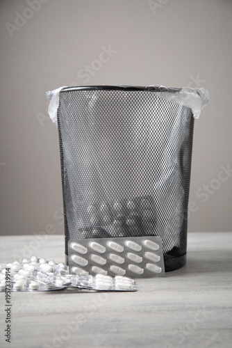 Medical pills and trash bin on the table.