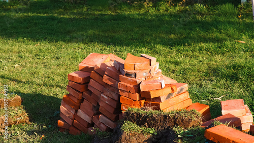 Pile of red bricks stacked on green grass in a construction area