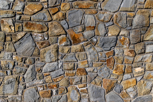 Gray and Brown Stone Wall Texture. Full frame view of an irregular gray and brown stone wall with mortar joints, showing rustic masonry texture and natural surface detail.