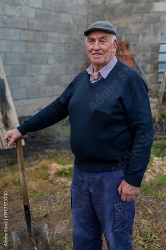 Elderly man with flat cap holding shovel