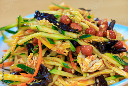 A close-up of Dongbei homemade cold salad. A salad of julienned cucumbers, wood ear mushrooms, Chinese cabbage, carrots, and peanuts dressed with a dressing. Chinese cuisine. Selective focus.