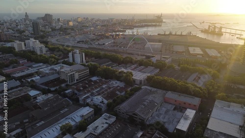 Cinematic aerial drone footage of Montevideo port during sunset, featuring harbor infrastructure, ocean views and warm golden light over the city coastline. Ideal for travel, business, and urban conte