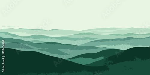 A misty mountain landscape at sunrise features layers of forest hills under a blue sky filled with soft clouds and morning haze over the valley.