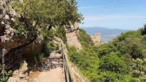 Walking in the mountains of Montserrat in Spain in summer. Panorama of mountain peaks and green plants against the blue sky. Trails for active recreation