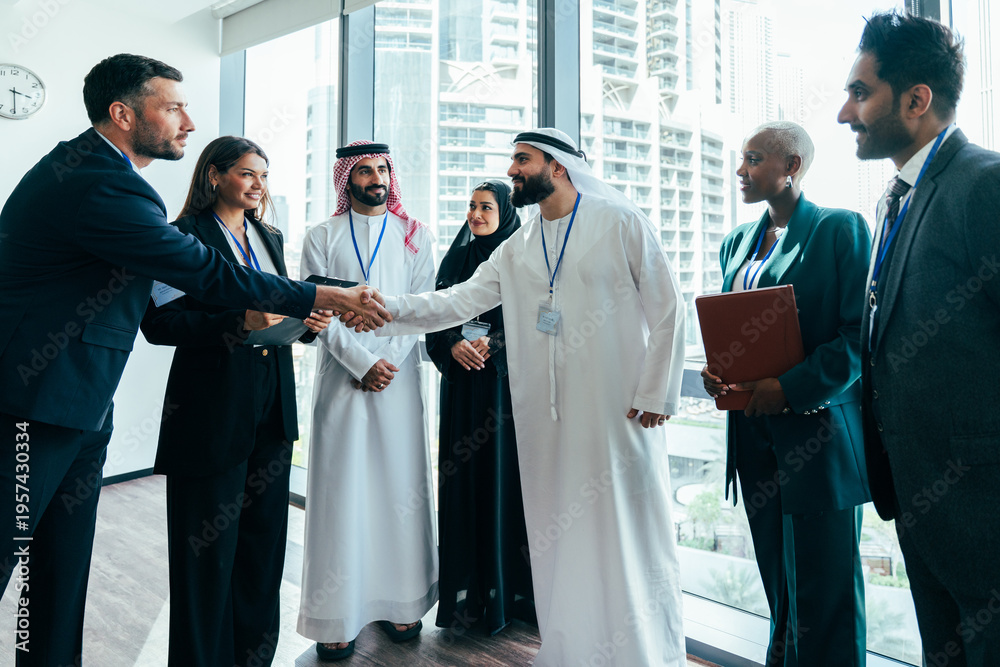 © oneinchpunch - Diverse business team shaking hands during corporate meeting in dubai