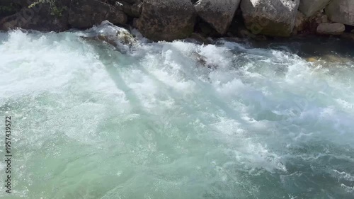 Clear clear emerald water in a mountain river. A sunny, warm day in Spain. Large stones on the shore to strengthen the riverbed.