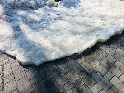 Tableau sur toile Melting snow on sidewalk in early spring city