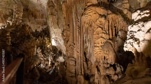 Limestone cave interior with stalactites and stalagmites illuminated in underground chamber