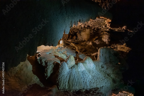 Limestone cave interior with stalactites and stalagmites illuminated in underground chamber