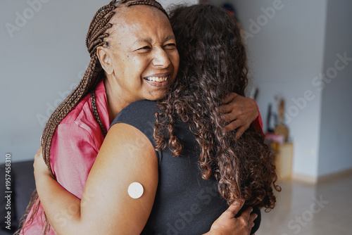 Tableau sur toile Happy african american mother hugging daugher with diabetes patch on arm at home