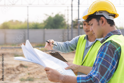Obraz na płótnie Builder team, foreman asian young engineer, architect man, male are discussing construction drawing on blueprint follow project to build an industrial plan at outdoor site