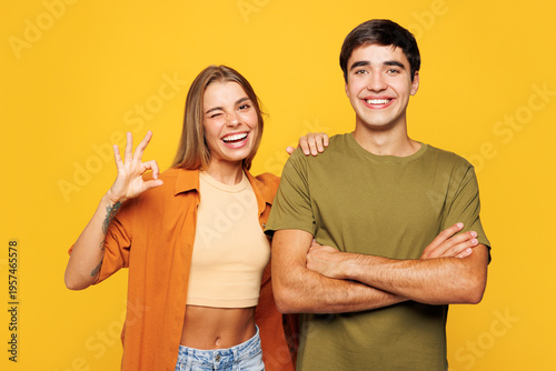 Young happy couple friends family man woman wears shirt casual clothes together put hand on shoulder look camera isolated on pastel plain light yellow background studio portrait. Lifestyle concept