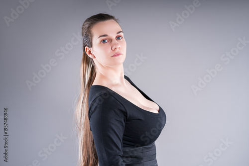 Curvy plus size fashion model in black bodysuit on gray background