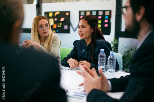 Billede på lærred Group of people having a discussion in an office with sticky notes on the wall a