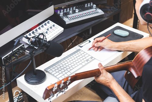 male musician writing a hit song by acoustic guitar in home studio