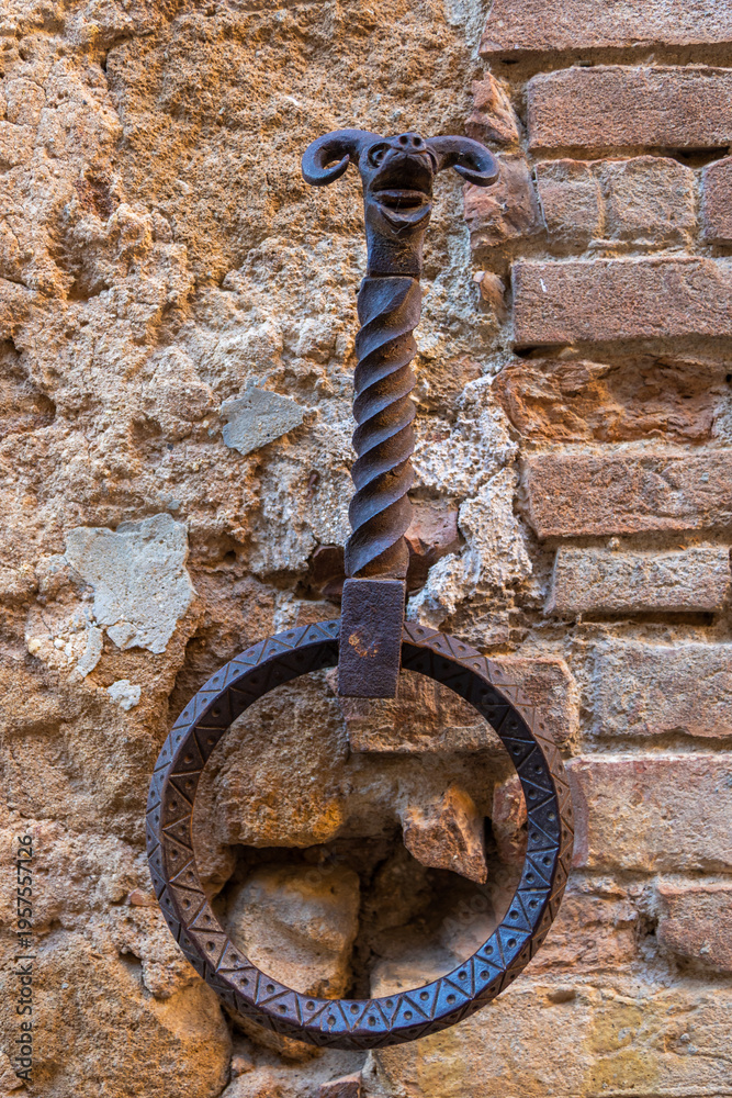 Fototapeta premium Ornate iron hitching ring with animal head on ancient wall in Pienza, Italy.
