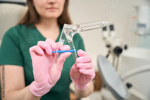 Tableau sur toile Adult woman in medical examination room holding swab and speculum