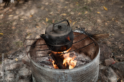 the kettle on a fire  at a campsite surrounded by stones during daylight hours
