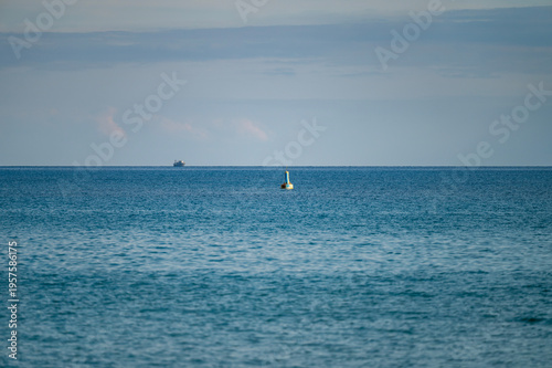 Navigation buoy on calm sea with distant ship