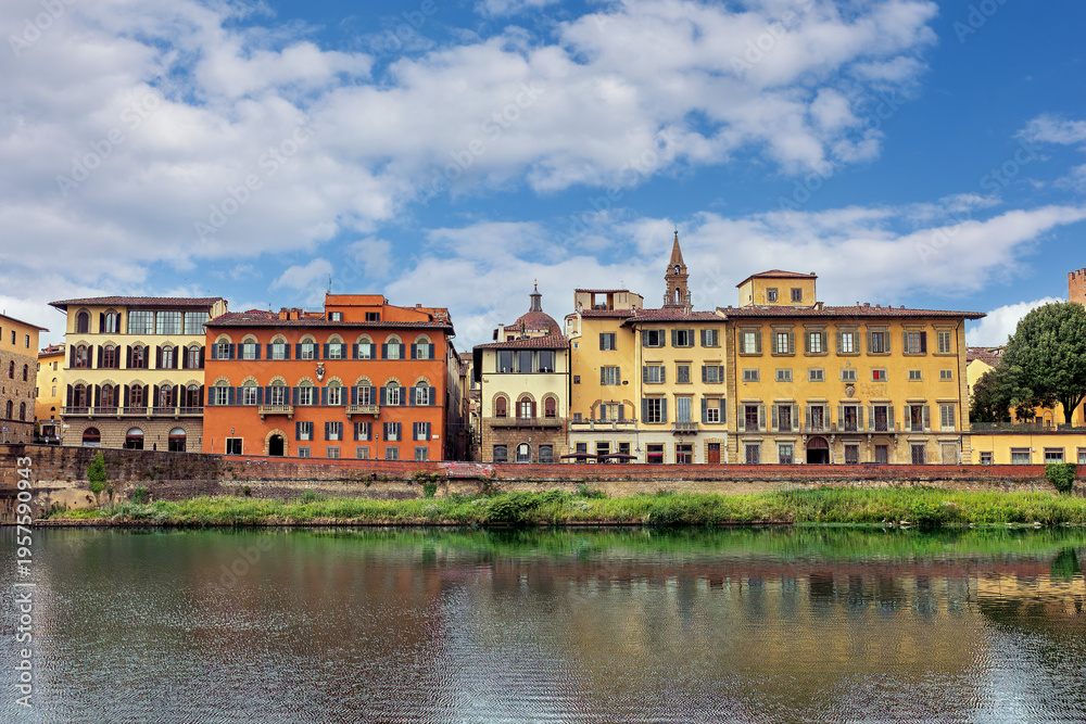 Fototapeta premium This scene highlights the Arno River along the Lungarno Torrigiani in Florence. Colorful buildings reflect in the water while the historic Palazzo Bardi-Guicciardini stands nearby.