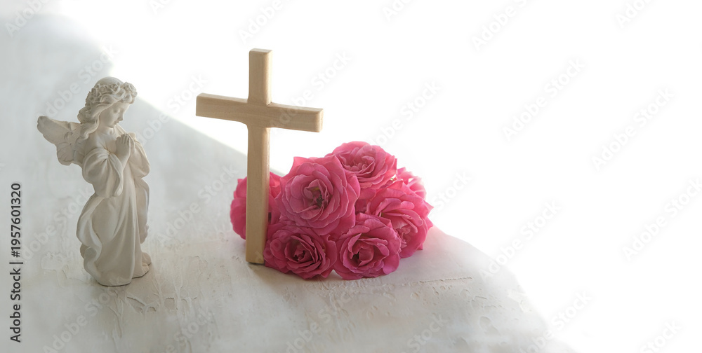 Obraz premium Easter holiday background. Beautiful angel figurine with wooden cross and pink rose flowers on light table close up. symbol of Easter, Christianity religion, faith in God, prayer, memory. copy space